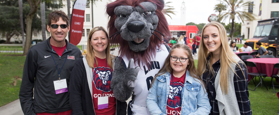 Family of four standing with Iggy the Lion