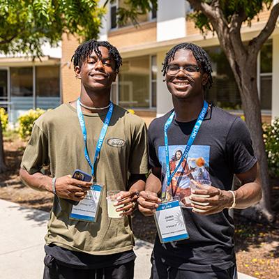 Two male students standing outside of a residence hall during move-in.