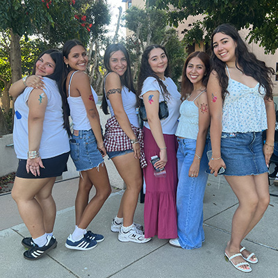 A small group of female students pose together outside of the residence halls.