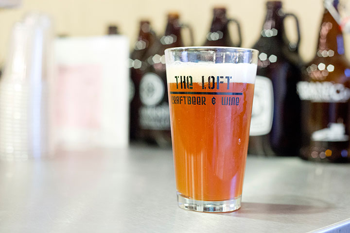 A pint of beer with The Loft Craft Beer And Wine written on the glass