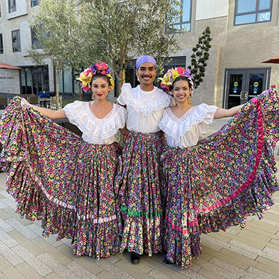 Three students pose in traditional Folklorico outfits.