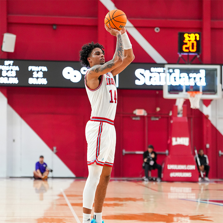 An LMU basketball player wearing a white uniform with number 14 takes a jump shot on an indoor court. The orange basketball is raised above the player's head, with the basket and shot clock visible in the background.