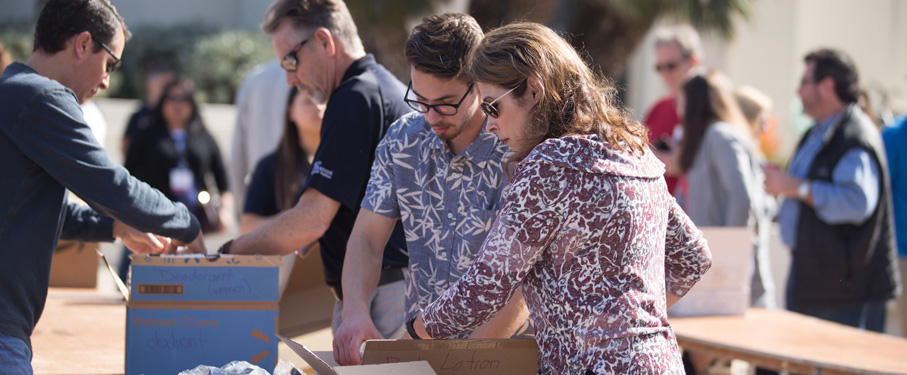 Mother and son standing outside filling brown boxes as part of the family service project