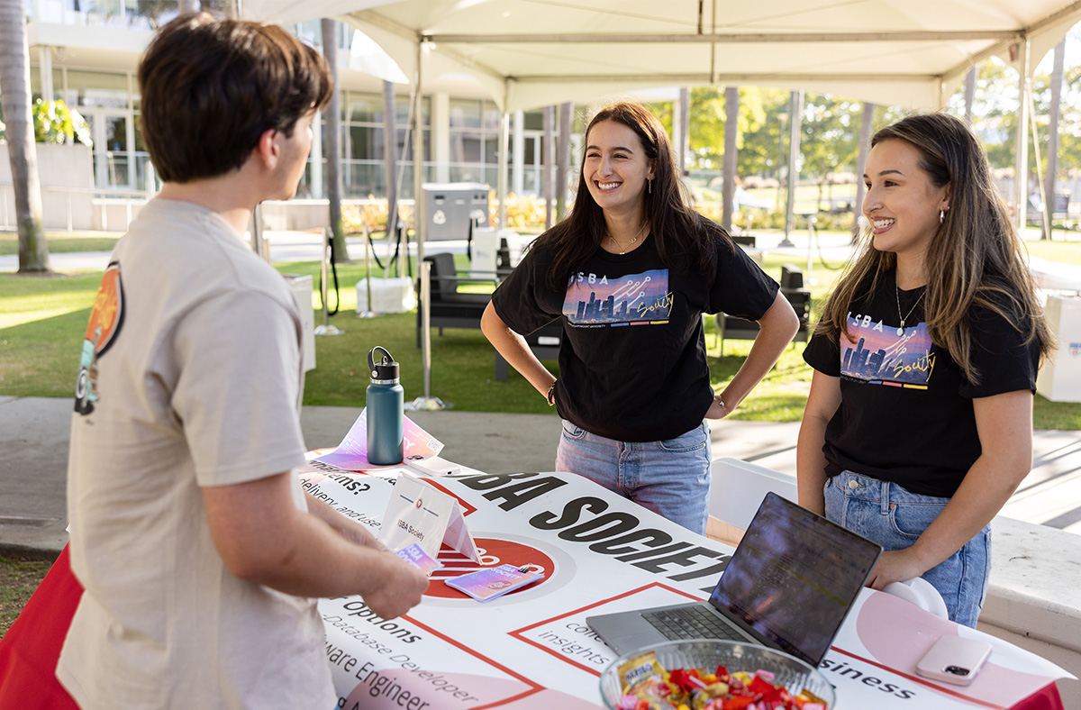 A group of male students gather at a table outside to meet new students during the annual Student Involvement Fair.